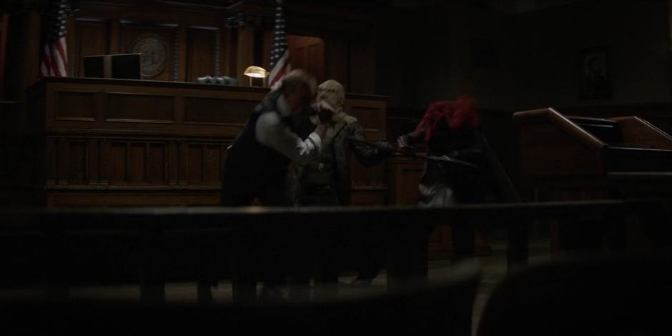 Kate holds back the Executioner's ax while Judge Calverick attempts to get away.