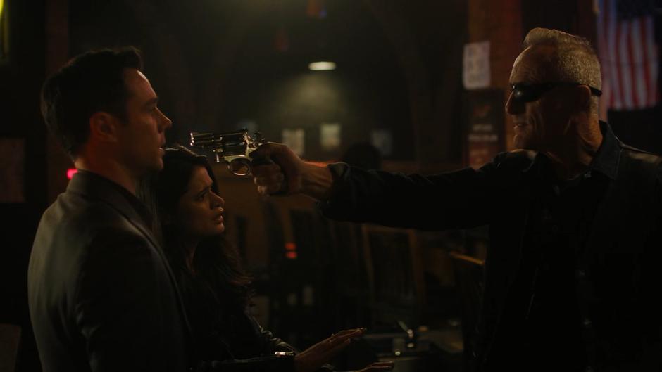 Mel tries to calm the situation as the demon who runs the bar holds his gun in Harry's face.