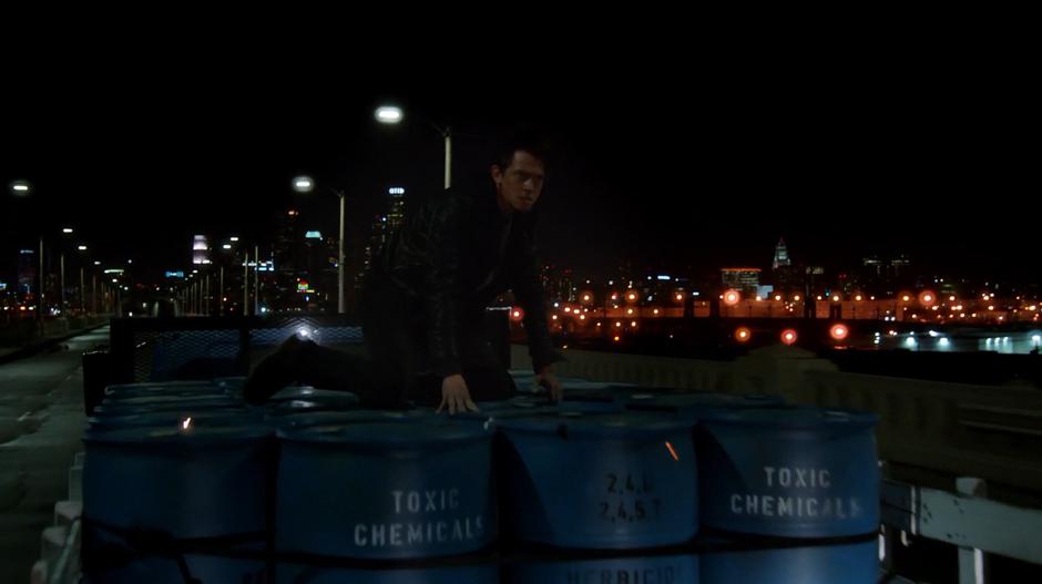 The Hellgrammite lands on top of the chemical barrels as the truck speeds across the viaduct.