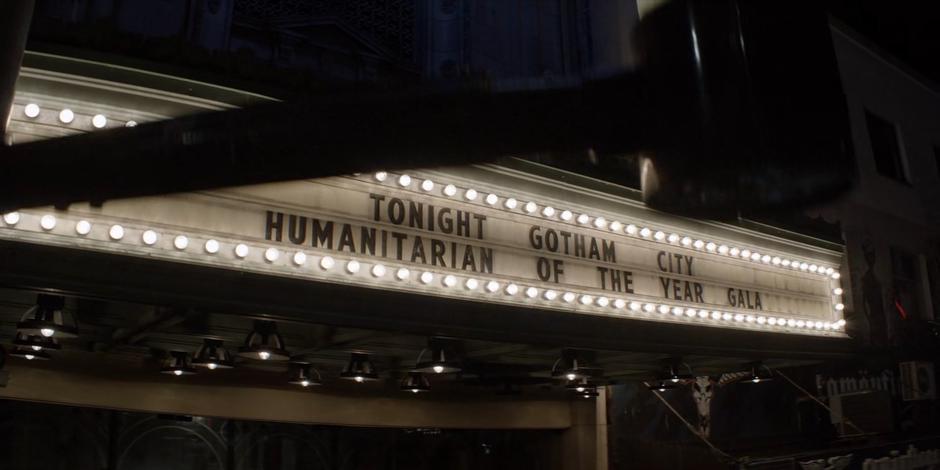 The marquee in front of the theater announces the "Gotham City Humanitarian of the Year" gala.