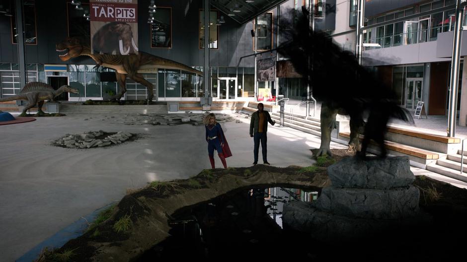 Kara and J'onn turn as Andrea attacks Rama Khan with her shadow form after he has risen from the tar pit.