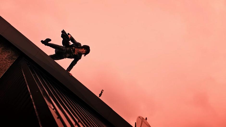 Helena Kyle leaps over the edge of the roof and slides down beneath the red sky.