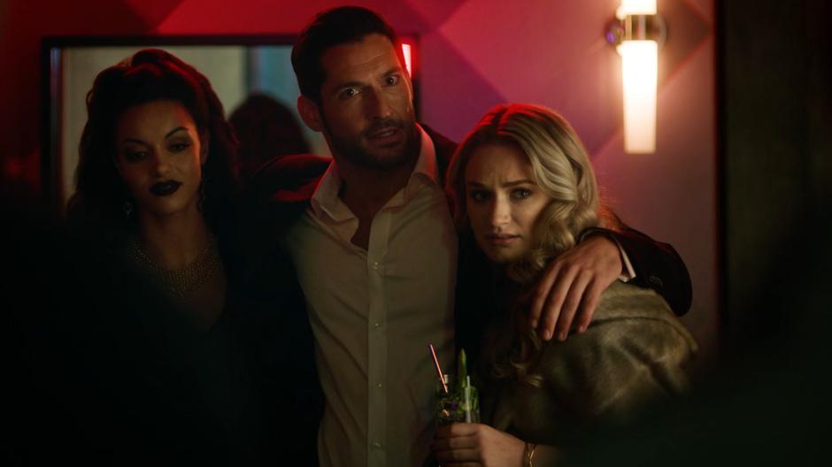 Lucifer opens the back door of his club with his arms around two women and sees Constantine standing outside.
