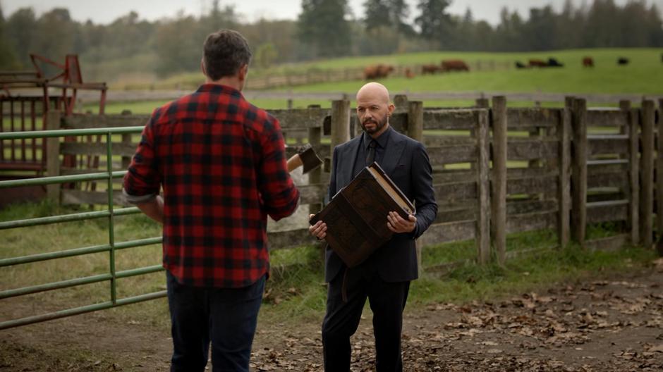 Earth-167 Clark holds up his ax while Lex approaches him with the Book of Destiny.