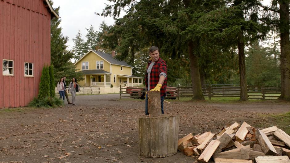 Lois, Clark, and Iris come around the corner of the barn to see Earth-167 Clark chopping wood.