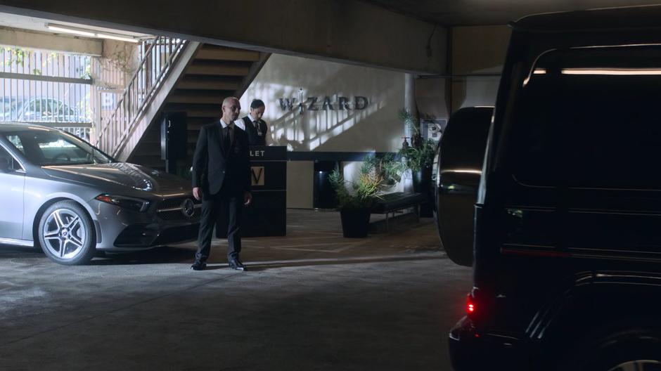 The security guard watches as Xavin does a poor job of driving Tina's car.