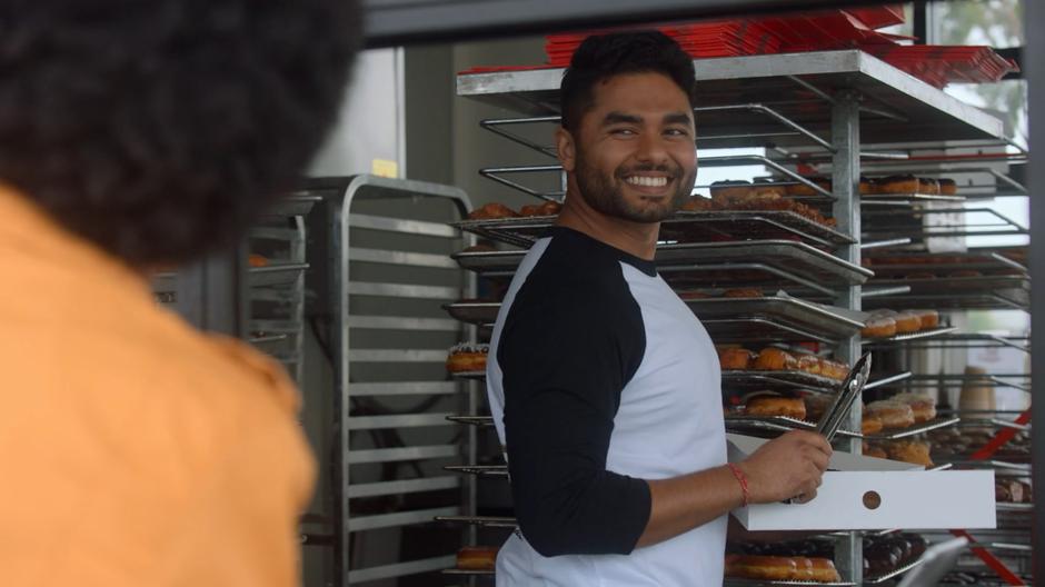 The donut store employee smiles at the Son after he orders another dozen donuts.