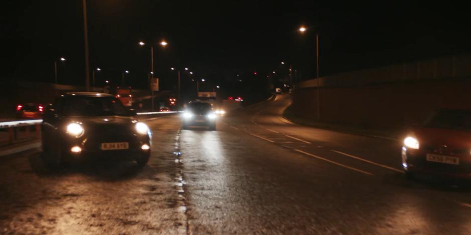 Cars swerve aside as the government vehicle drives itself backwards towards the tunnel.