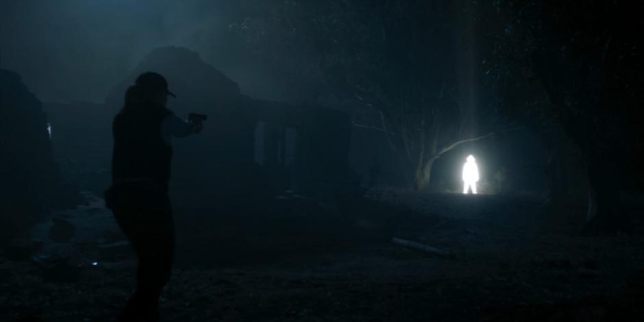 Browning points her gun at one of the mysterious figures made of light as it appears in the distance.