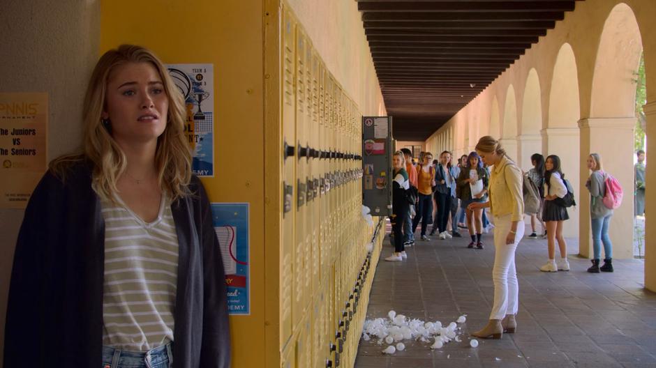 Karolina leans back on the lockers in mortification as a bunch of lightbulbs fall out of he past self's locker.