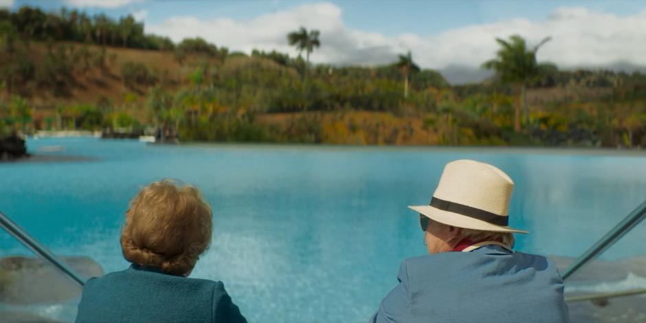 Vilma and Benni sit at the edge of the pool looking out of the landscape.