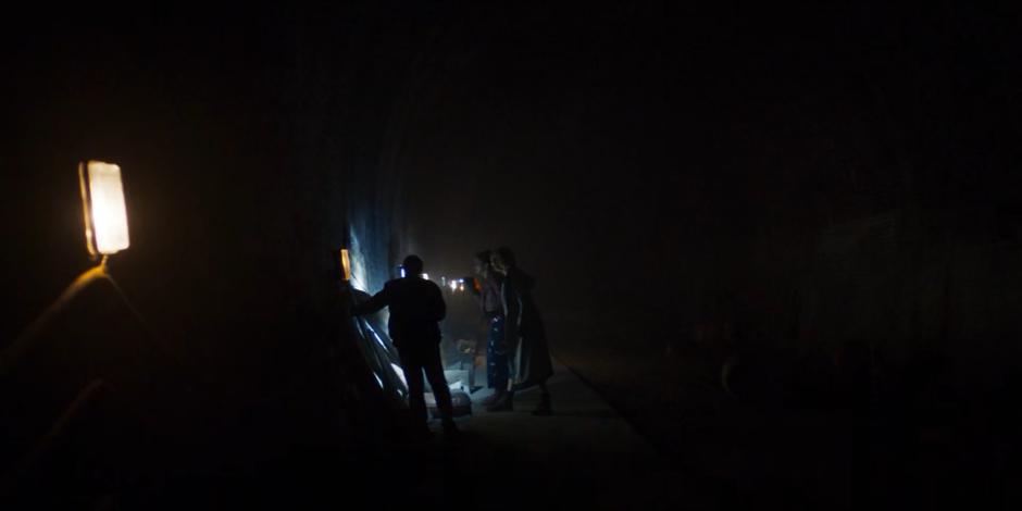 Ryan, Yaz, and the Doctor examine the old Earth subway sign on the wall of the tunnel.