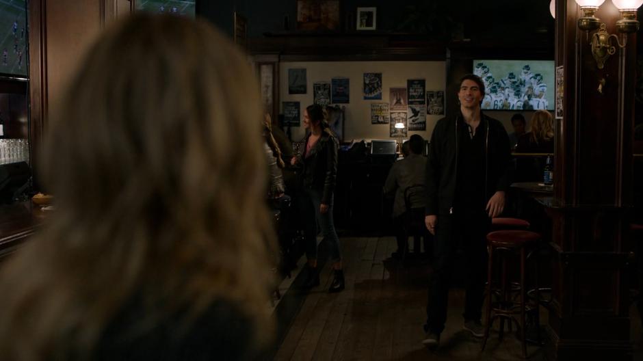 Ray smiles and walks over to Sara when she enters the bar.