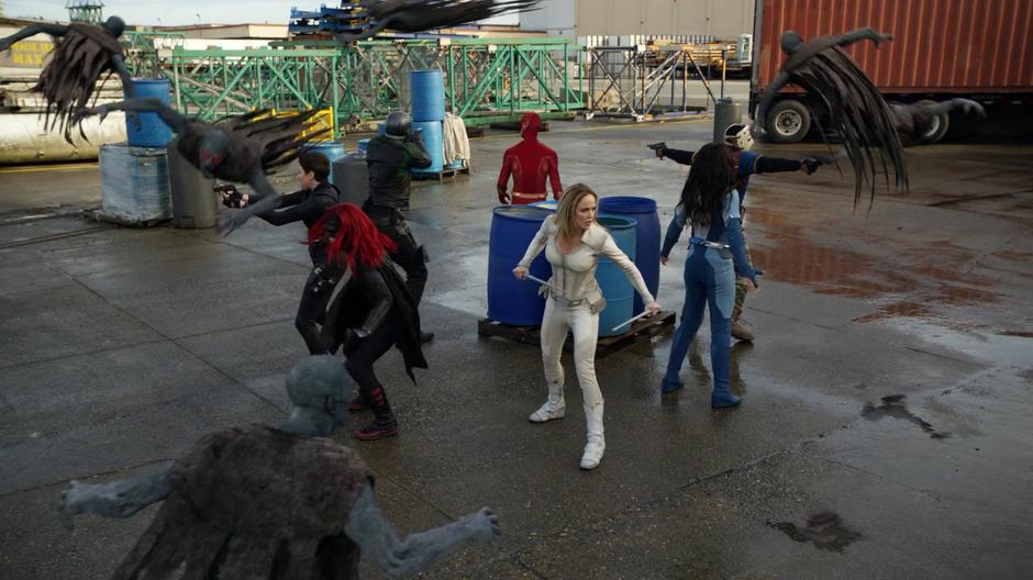 Alex, Kate, Diggle, Barry, Sara, Nia, and Rene stand in a circle fighting off the shadow creatures.