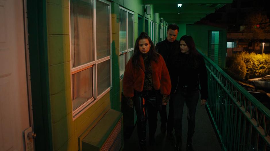 Maggie, Harry, and Mel walk along the upper floor of the motel searching for the room from Maggie's vision.