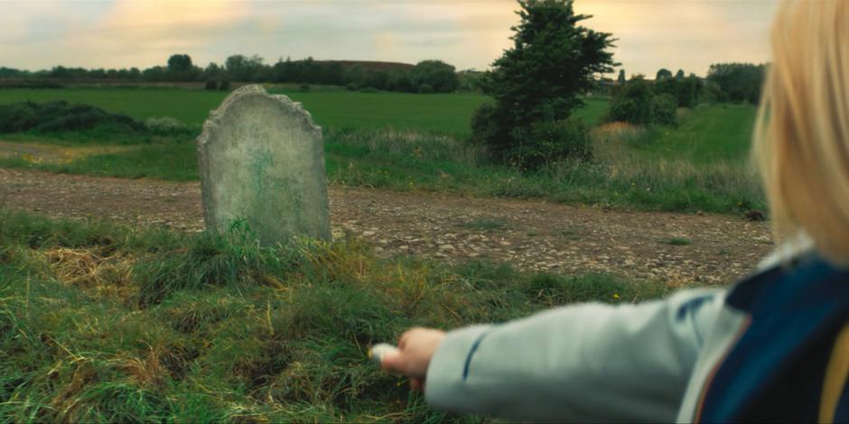 The Doctor scans the ground beneath the blank gravestone.