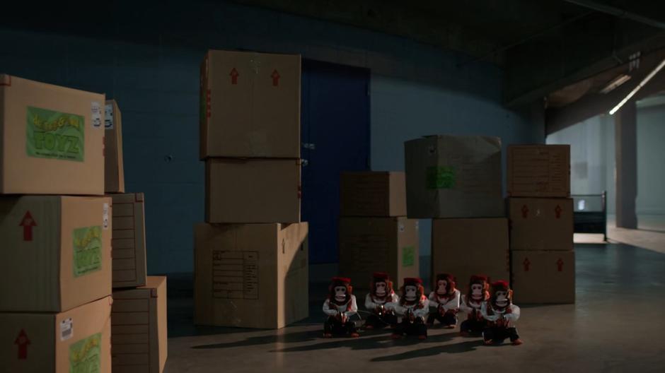 A group of toy monkey's rigged to explode sit in a pile of boxes.