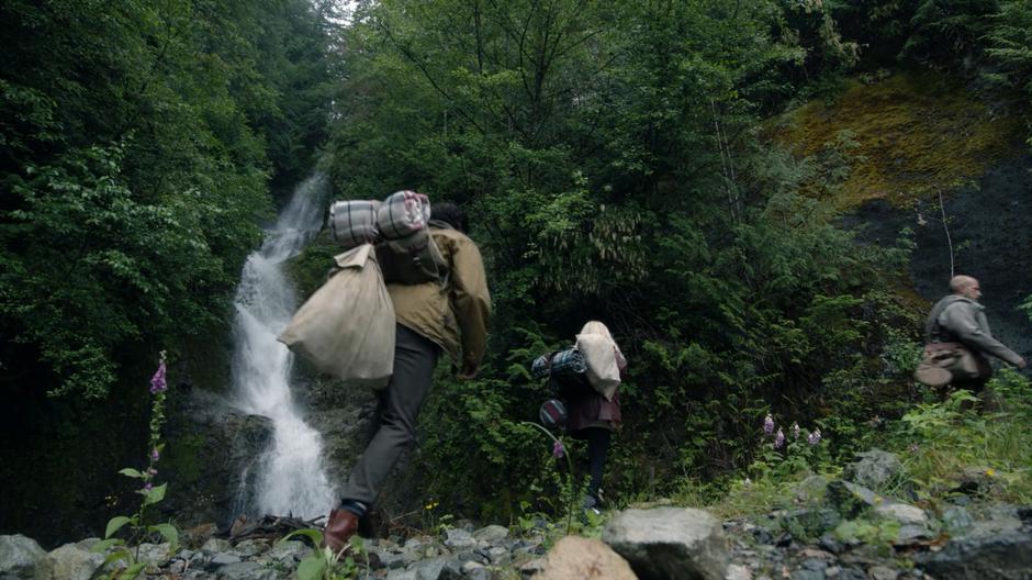 Eliot and Alice follow the guide up the path past the waterfall.