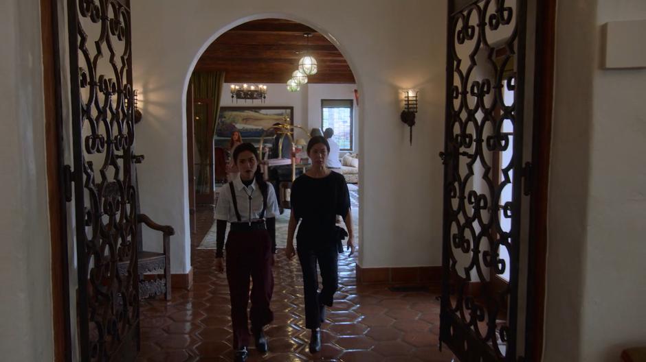 Nico and Tina walk through the lobby towards Morgan's office.