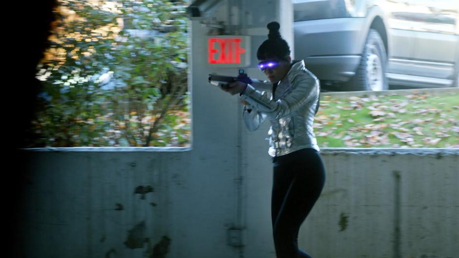 Kimiyo Hoshi hops down into the garage and walks towards Iris with the light rifle raised.
