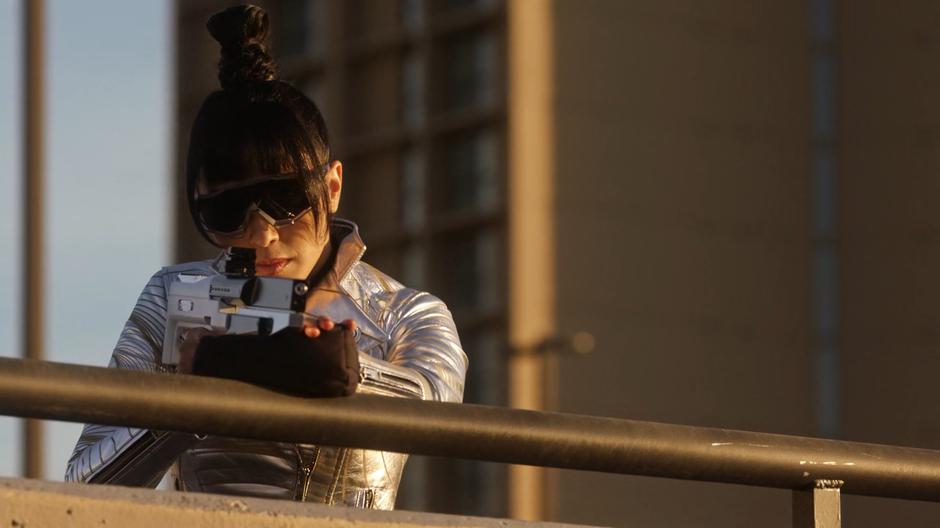 Kimiyo Hoshi places the stolen infrared photon rifle on the railing and aims it towards the offices across the way.