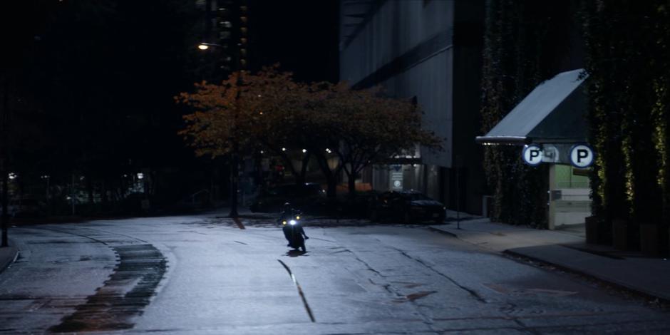 Kate rides her motorcycle down a deserted road at night.