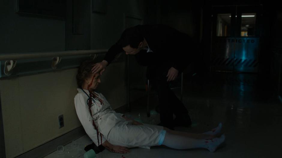 Harry leans down to examine the bullet hole in the nurse's head.