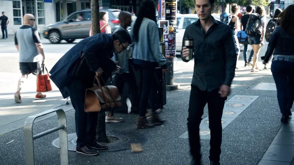 Gary drops something to the street while struggling with all of the stuff he is carrying for Constantine.