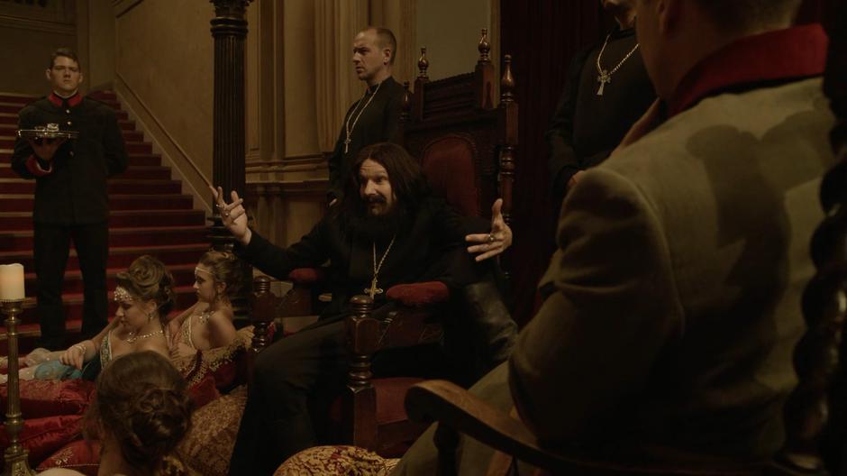 Rasputin lounges on his thrones surrounded by women and servants and talks to Nate.