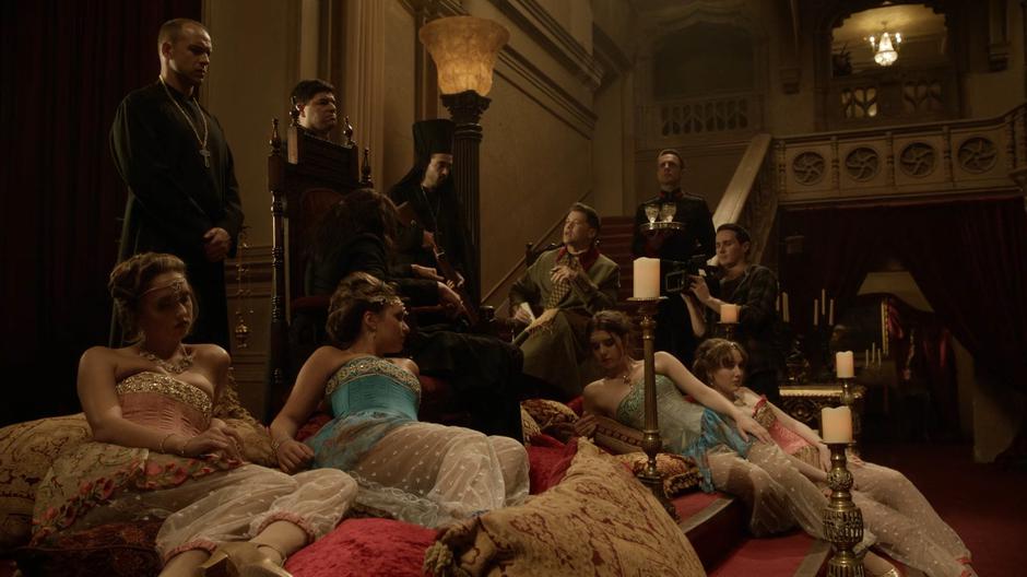 The camera operator films while Nate interviews Rasputin on his throne surrounded by women and servants.