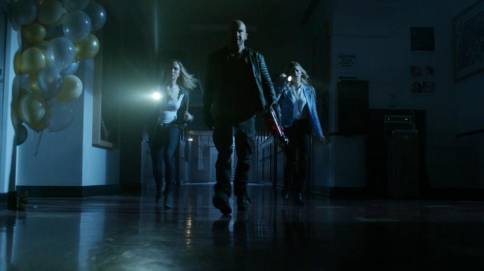 Sara, Mick, and Ava rush down the hallway searching for the killer.