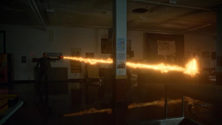 Mick shoots a blast of fire at the killer in the cafeteria.