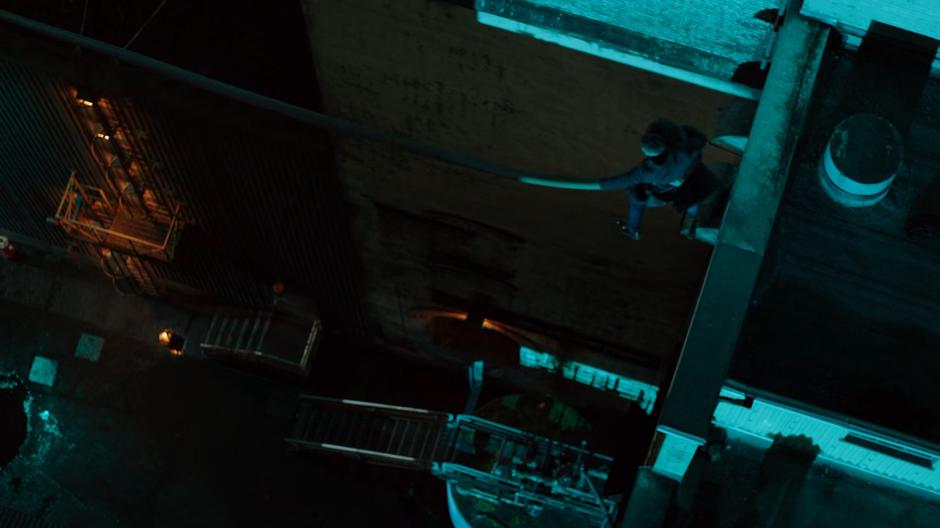 Ralph leaps off the roof with his arm stretched to a nearby beam while holding Sue.