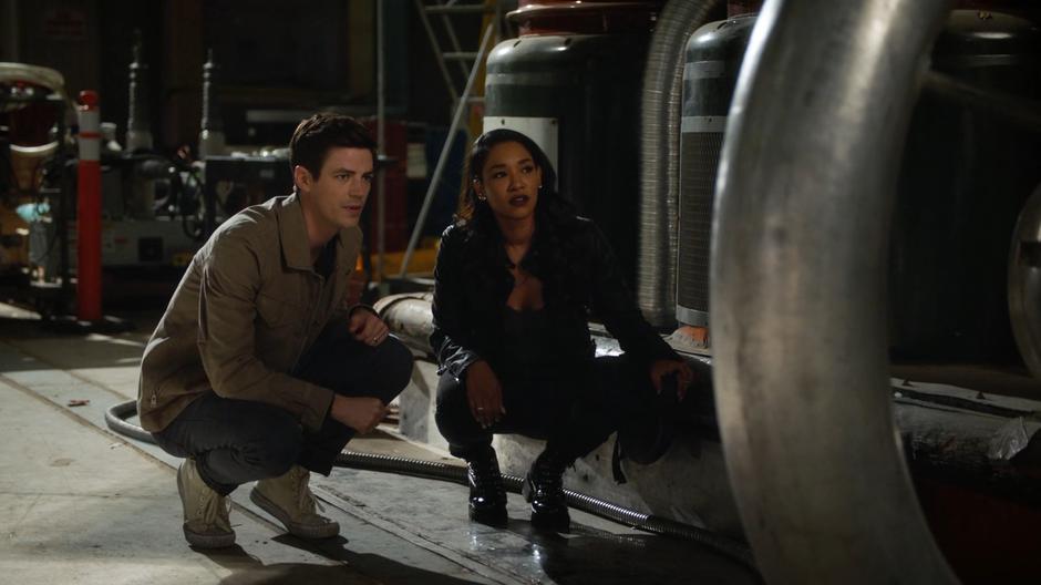 Barry and Iris crouch behind some equipment and watch Amunet steal from the safe.
