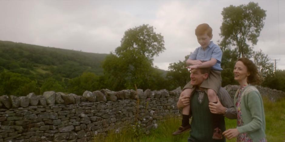 Young Brendan rides on Patrick's shoulders while Meg walks beside them.