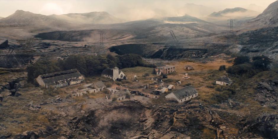 A handfull of ruined buildings remain standing in the middle of a desolate bombed-out landscape.