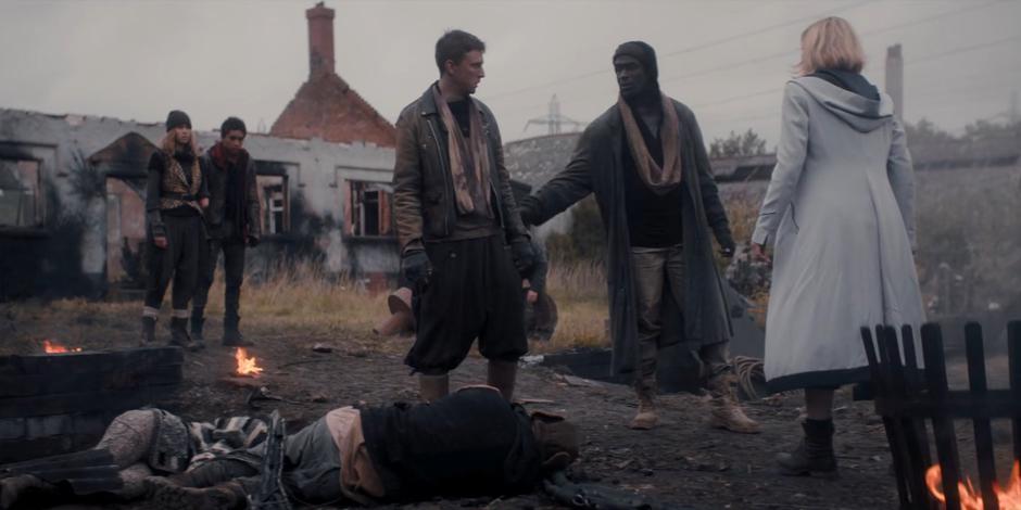Bescot and Ethan watch as Feekat and the Doctor talk to Yedlarmi over the body of Fuskie.