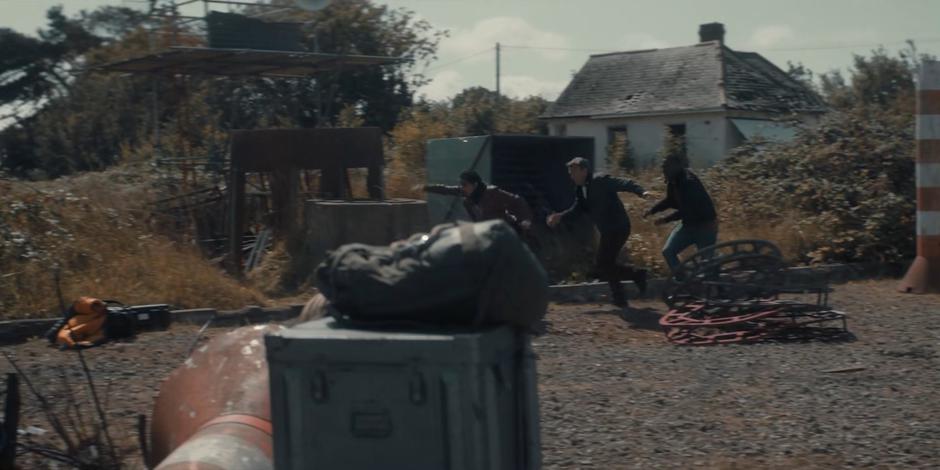 Yaz, Graham, and Ryan run across the camp towards the human ship as the Cybermen attack.