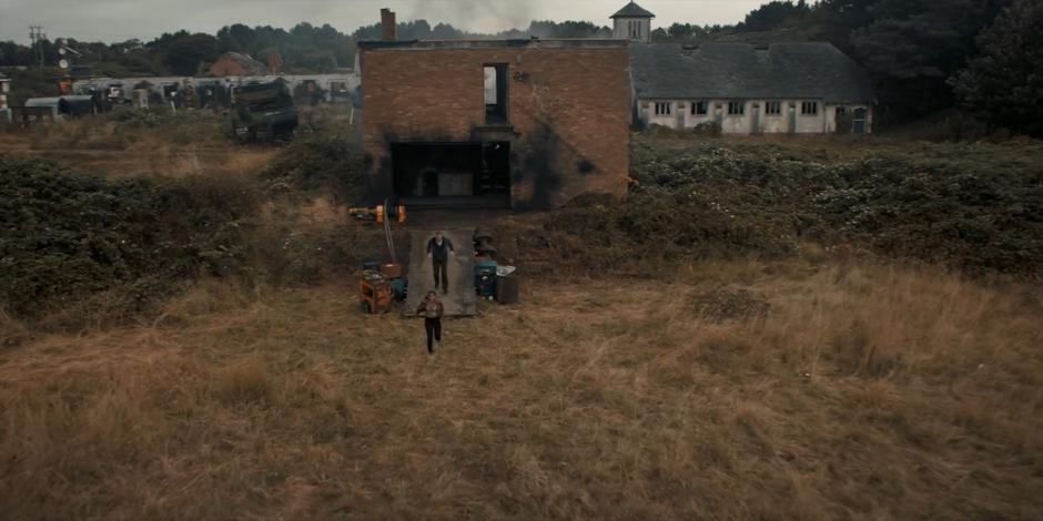 Yaz and Graham run from a ruined building towards the waiting ship.