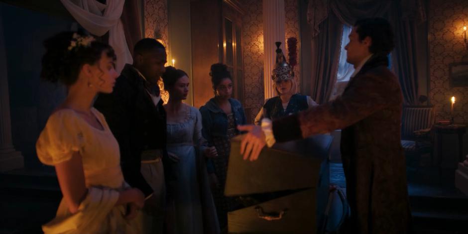 Claire, Ryan, Mary, Yaz, and the Doctor watch as Byron opens up his box of bones.