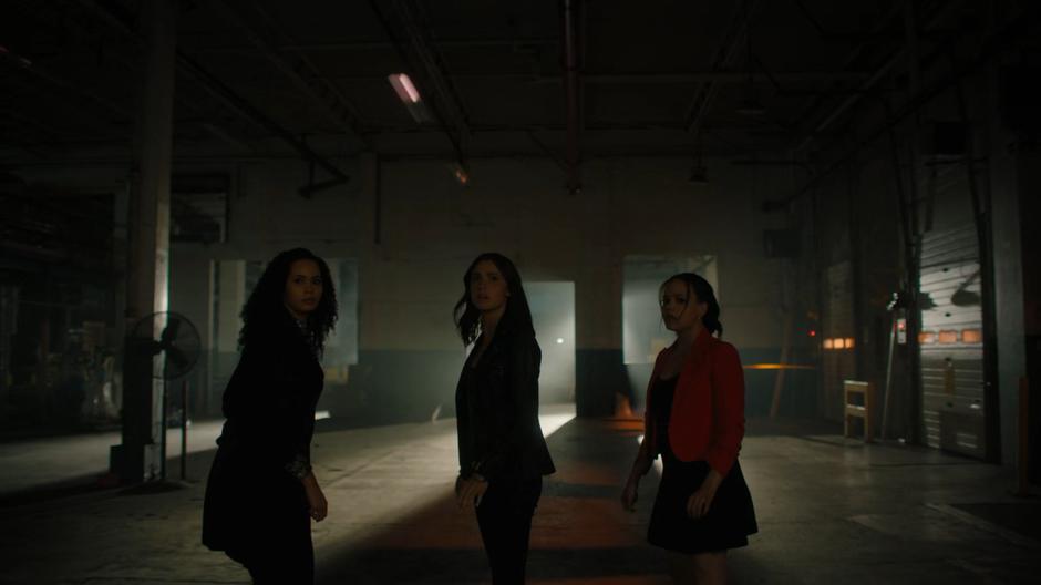 Macy, Abigael, and Maggie look around after emerging from the portal into a dark building.