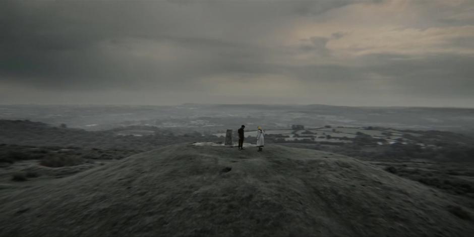 The Master and the Doctor talk on top of a black & white hilltop.