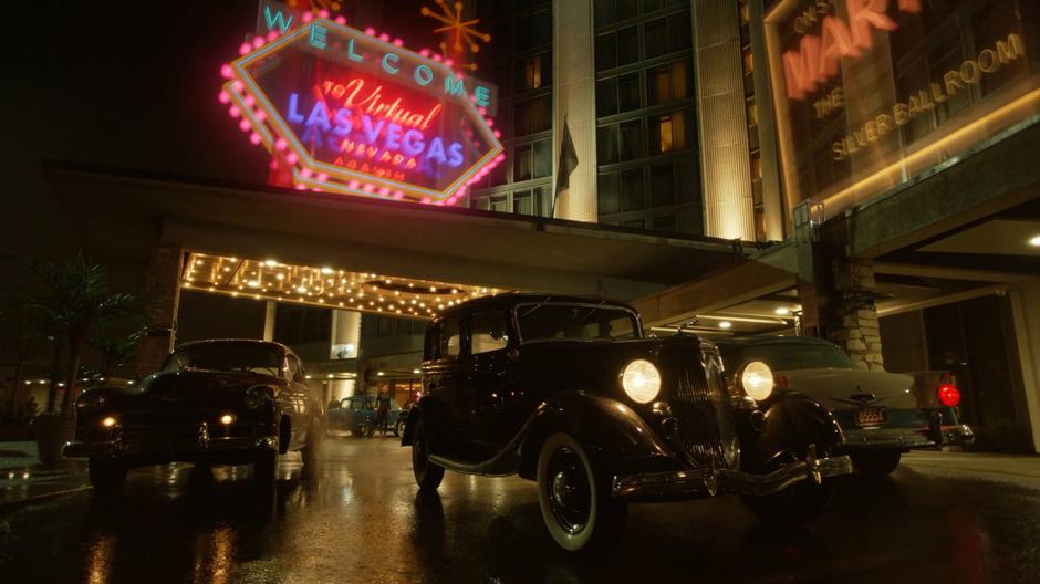 Alex appears in the simulation out front of the casino as classic cars drive past.