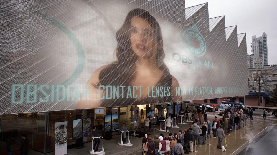 Andrea appears on a massive screen on the side of the building as people wait in line to test out Obsidian Platinum.