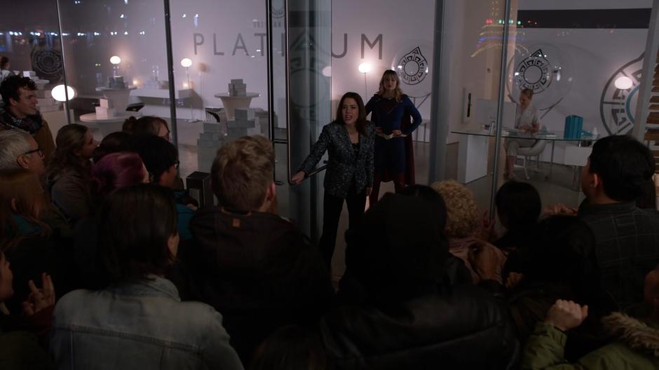 Kara watches from behind as Andrea opens the door of the store to a crowd of fans.