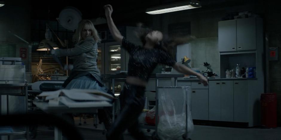 Alice knocks Mary out with a medical tray.