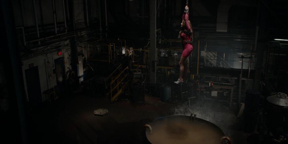Veronica May hangs from a chain over a vat of chemicals as Duela Dent gives her whole speech.