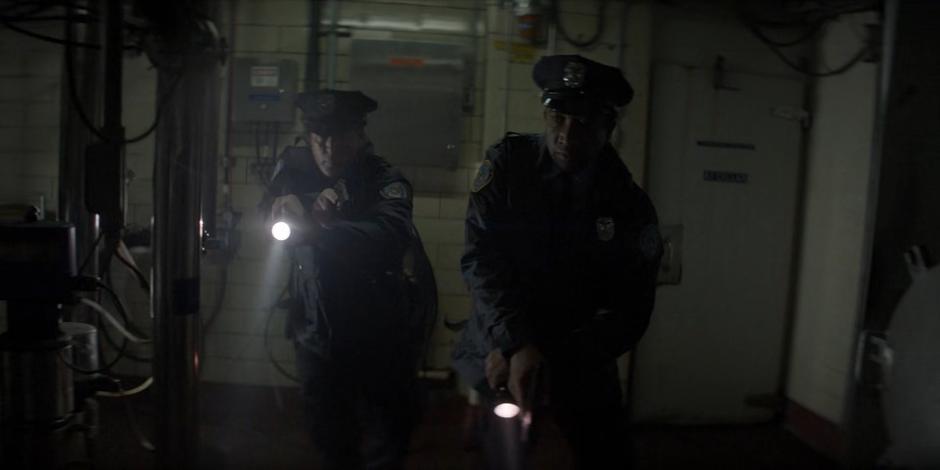 Two police officers search through the factory.
