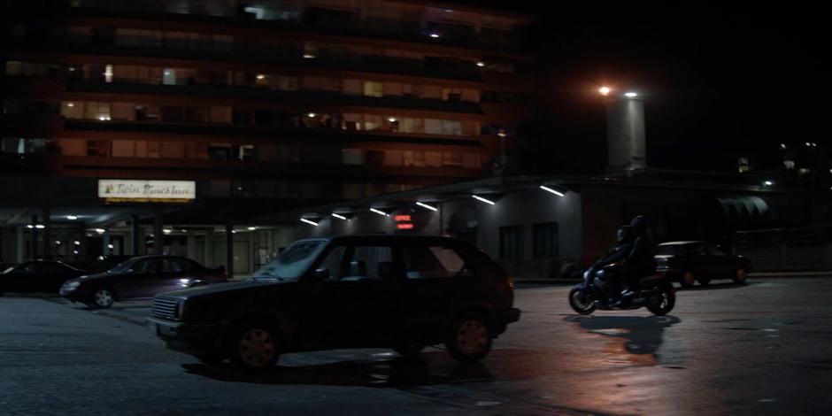 Luke turns the Batcycle into a parking spot in front of the motel at night with Beth.