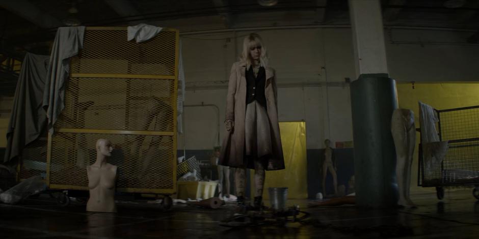 Alice looks down at a bear trap on the floor of the warehouse.